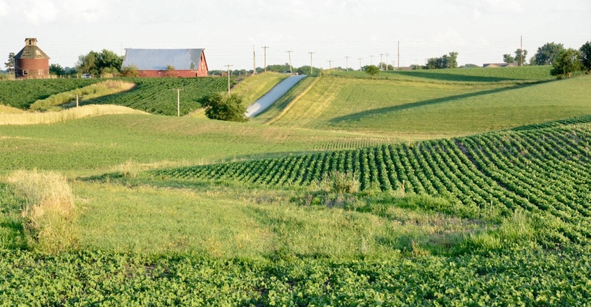 Country road with red barn, rolling hills, and farmland.