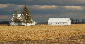 white farm buildings in harvested cornfield