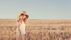 woman wearing wide brimmed hat in wheat field