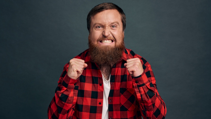 angry, stressed bearded man looking at the camera with clenched fists and teeth