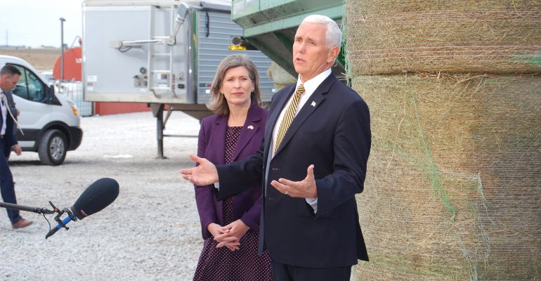 Vice President Mike Pence next to a woman speaking at  an Iowa farm 