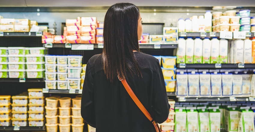 Woman shops the dairy aisle of a grocery store