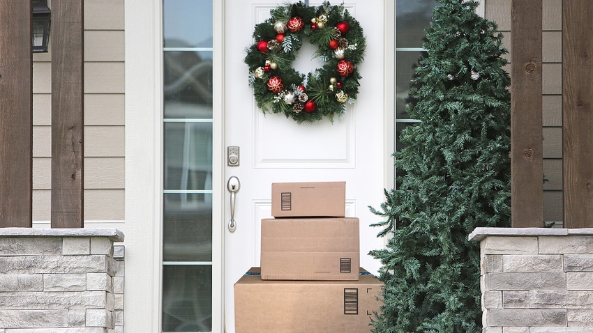 Front door of a home with a holiday wreath and a stack of brown packages on the doorstep.