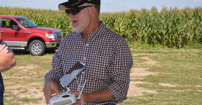 Bob Nielsen shows a farmer how to use equipment to view images from a drone flying over a farm field
