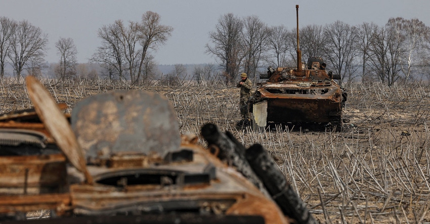 A Ukrainian soldier checks the wreckage of a burnt Russian tank