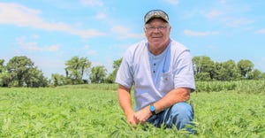 Farmer Jeff Limbaugh kneeling in a hemp field 