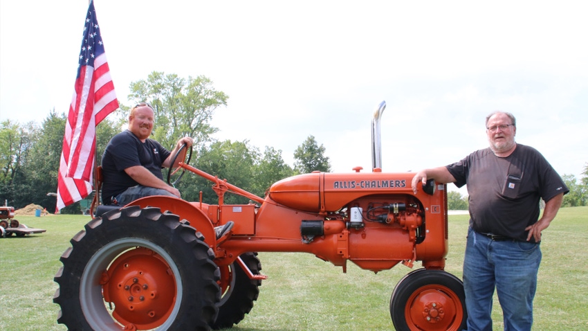 Landon Lauer sitting on Allis-Chalmers C tractor while Dad Richard Lauer stands next to the tractor