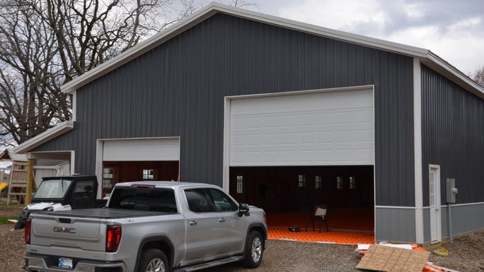 exterior view of farm shop with garage doors open while orange Creatherm panels are put down to in