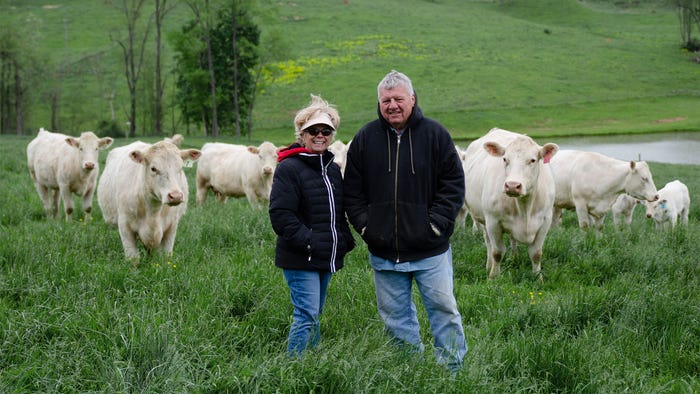 Julius and Jodee Verhovec stand in a field surrounded by cattle Julius and Jodee Verhovec stand in a field surrounded by cattle