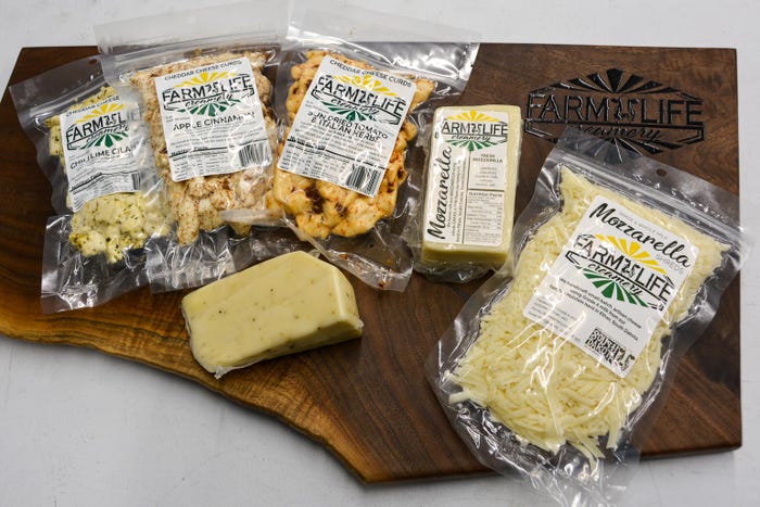 A close up of a wooden board with various packaged cheese products on display