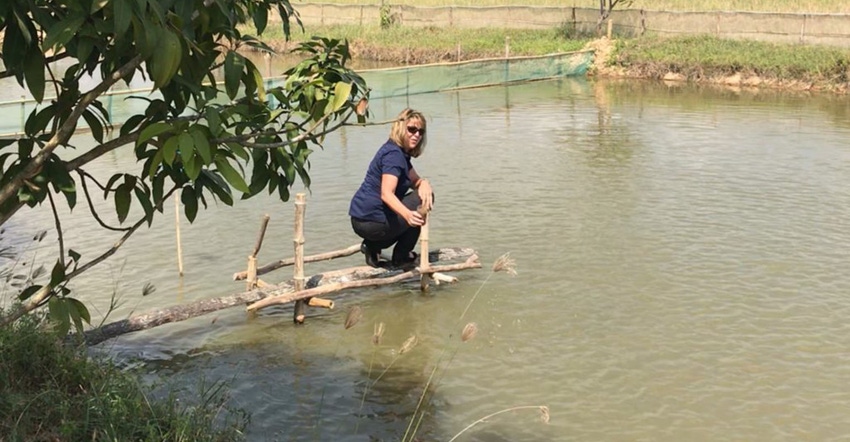 South Dakota soybean farmer Dawn Scheier feeds fish during her trip to Cambodia.