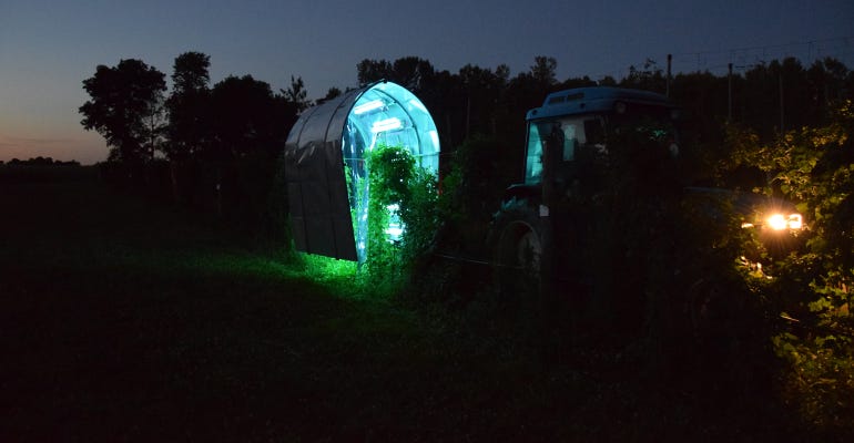 UV light treatments glow from an enclosure in the field shown at night