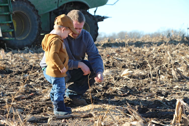 Troy Meinke helps his son, Thomas, dig in the ground