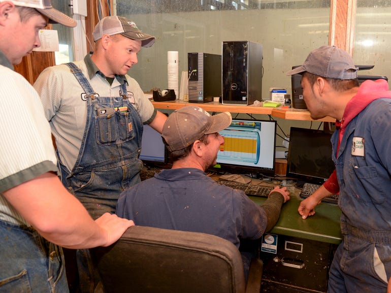 Garrett Miller checks a computer screen for automated health alerts with other herdsmen