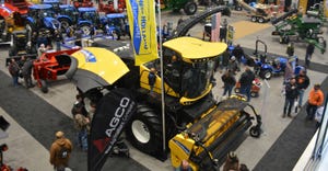 A yellow tractor showcased at an exhibition surrounded by spectators