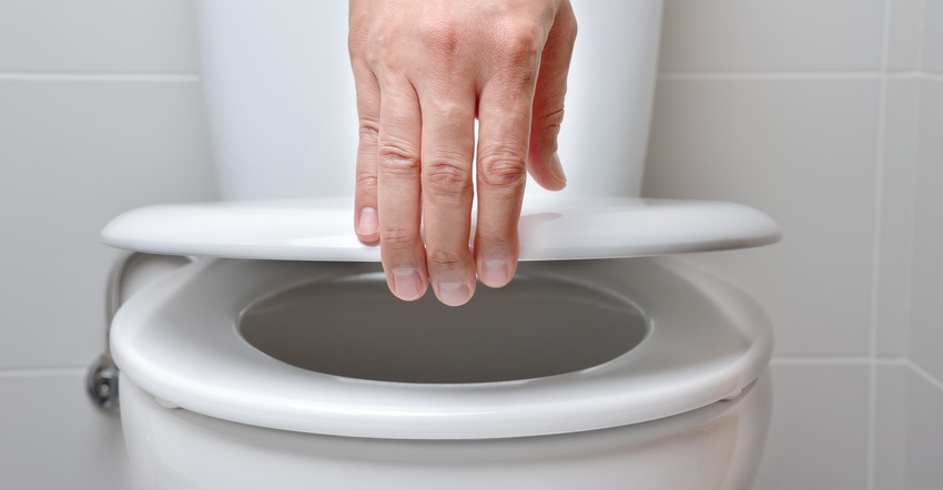hand of a man closing the lid of a toilet