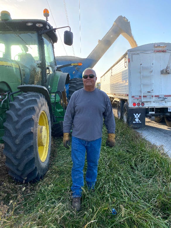 Tim Mershon in field with tractor, combine and grain truck