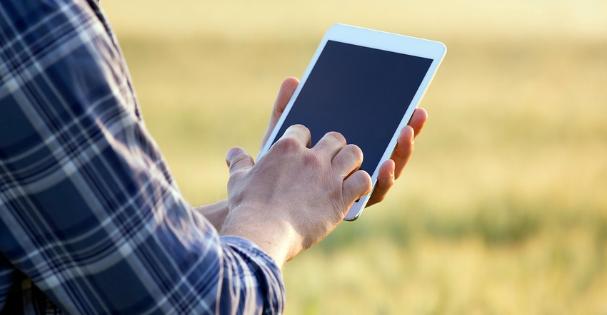 farmer holding tablet in wheat field