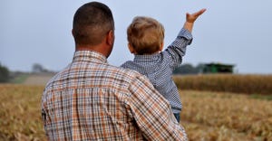 male farmer holding son in field