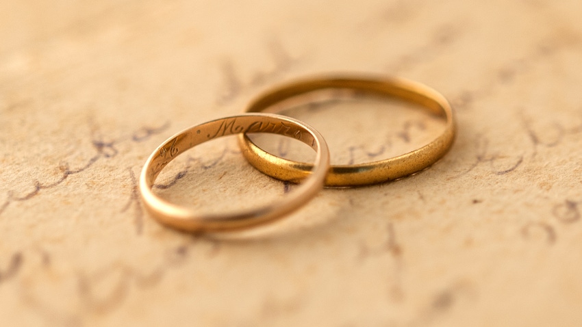  two gold rings sitting on top of old paper