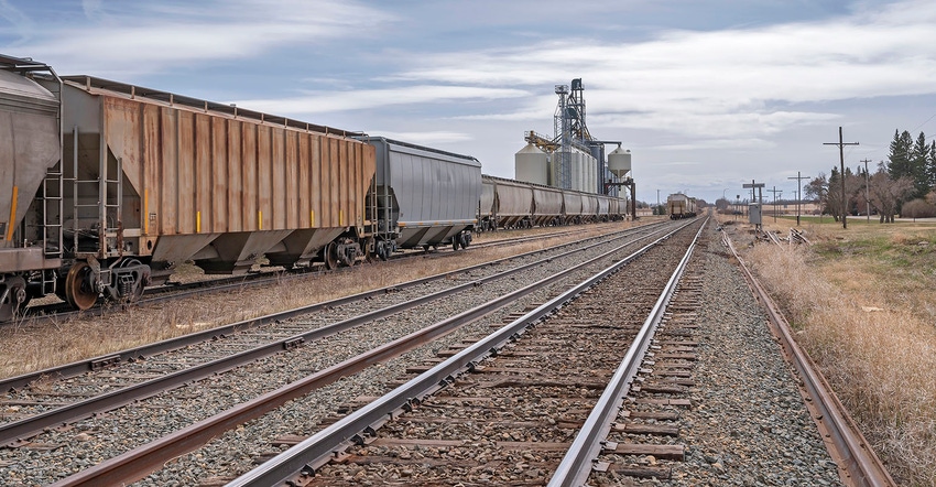 Train with grain elevator in background.