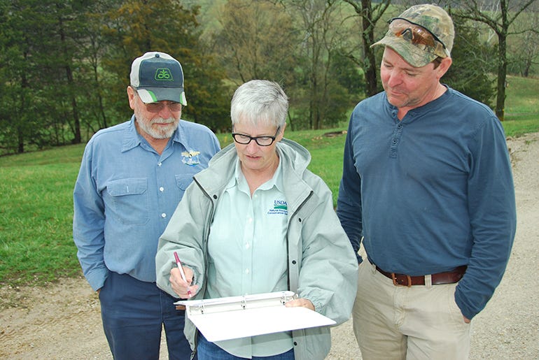 Wilmer Erfling (left), talks with NRCS District Conservationist Tammy Teeter and his son Jason 