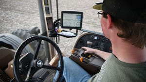 A young man monitoring a planter while inside the cab
