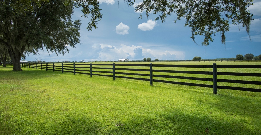 green farmland pasture surrounded by fence