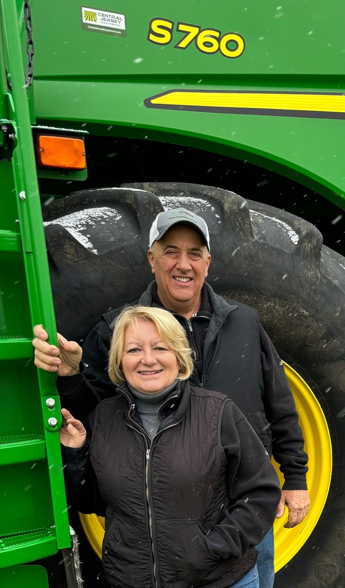 Chris and Sam Santini smile for a photograph in front of a tractor
