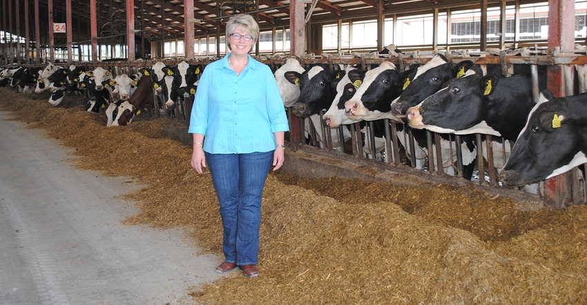 Janina Siemers stands in cow barn full of Holsteins