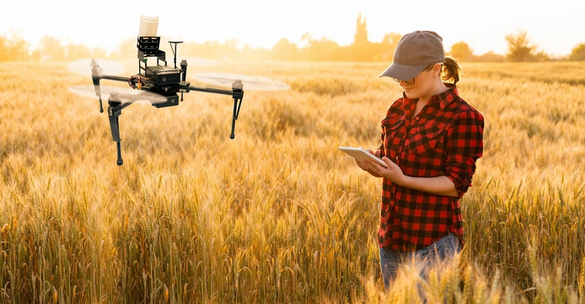 A female farmer controlling a drone sprayer with a tablet