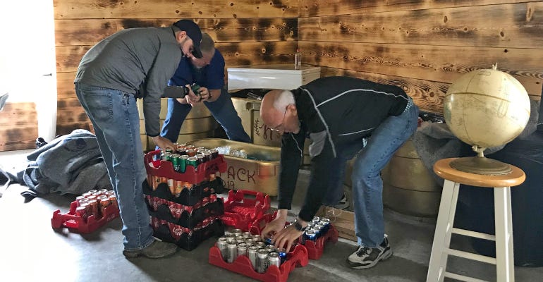 3 men arranging canned beverages