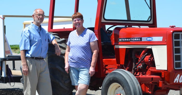 Dick and Carolee Ourada standing next to "Aggie,” their 1977 IHC 574 tractor and a trailer