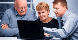 Elderly couple reviews documents at home on a laptop with their financial planner