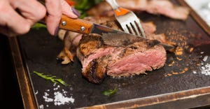 woman's hands cutting steak on a platter