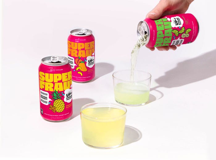 Courtesy of Super Frau - Bright and colorful drink cans against a white background as one can is being poured into a clear cup