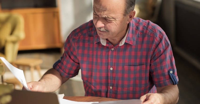 Man evaluating a piece of paper on a desk in concentration. Man evaluating a piece of paper on a desk in concentration.