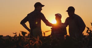 farmers talking and shaking hands as sun sets