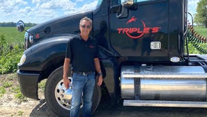 Scott Smith smiles while he stands next to a semitruck