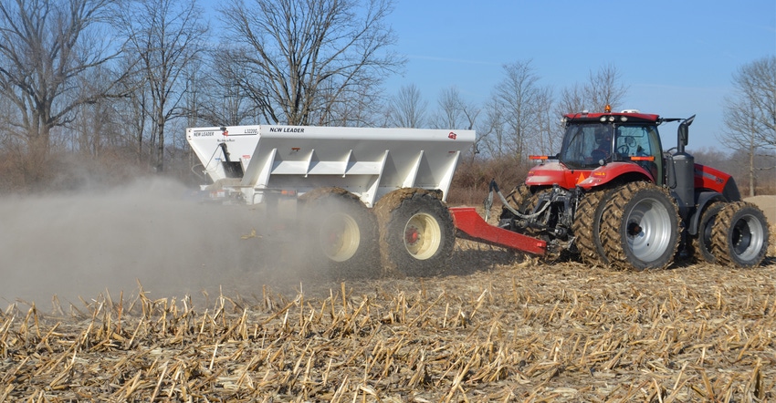 A red tractor applying lime to soil