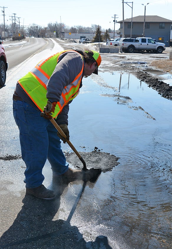 MnDOT worker fills pothole under water