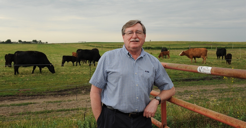 Mark Rasmussen standing in field with cattle in the background Mark Rasmussen standing in field with cattle in the background