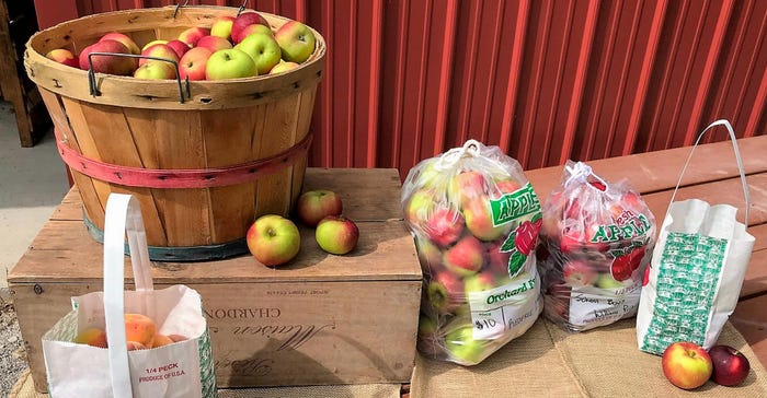 A basket and various bags filled with apples