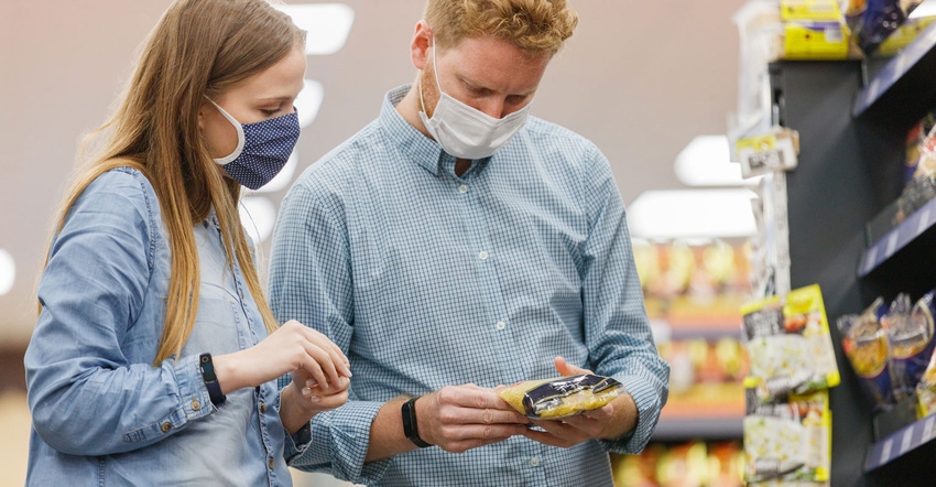 A young couple wearing face masks as they shop and read a nutrition label