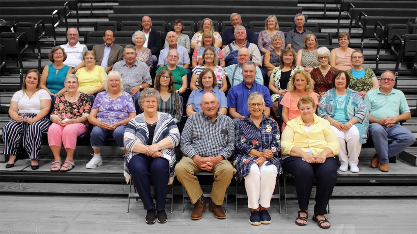  A group of 33 men and women sit in rows on bleachers and smile