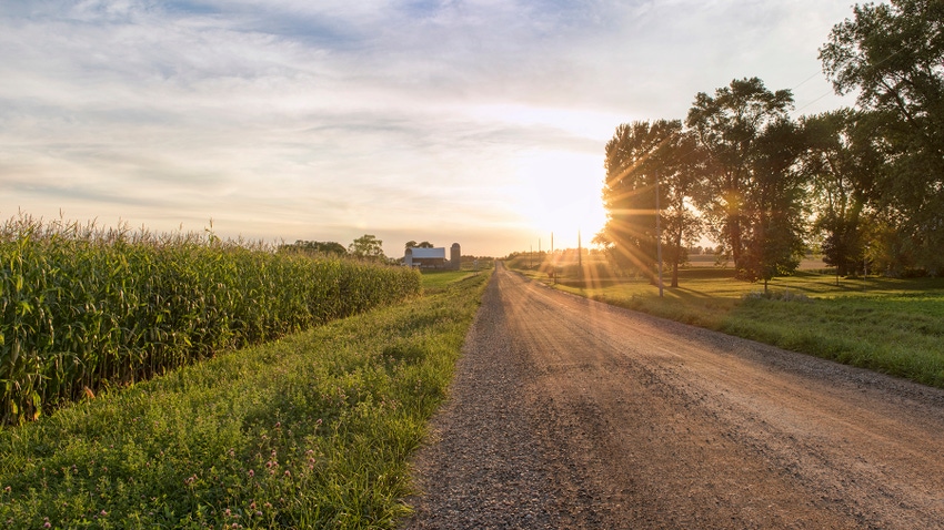 Sunset over rural gravel road and farmstead