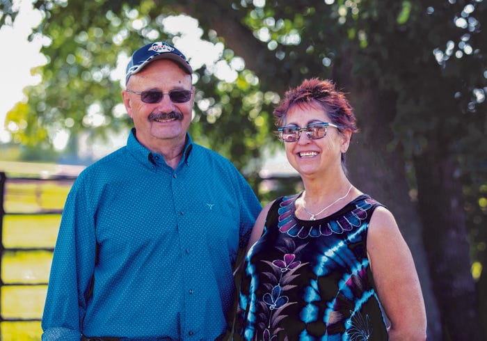 Gene and Christine Goven posing together in front of a tree and fence