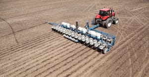 A low aerial view of a tractor planting a cornfield. 