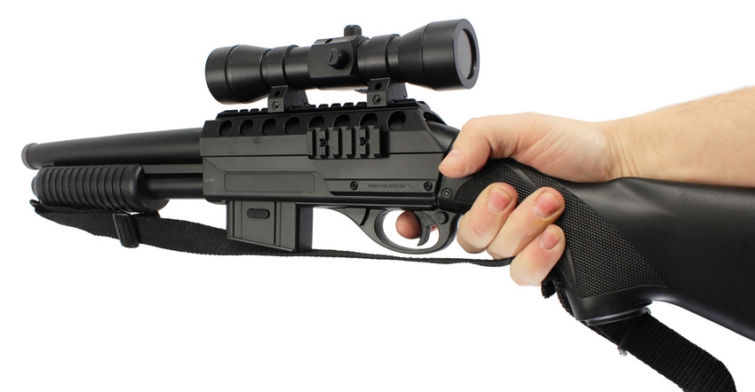A Caucasian hand holding a black short barreled shotgun A Caucasian hand holding a black short barreled shotgun