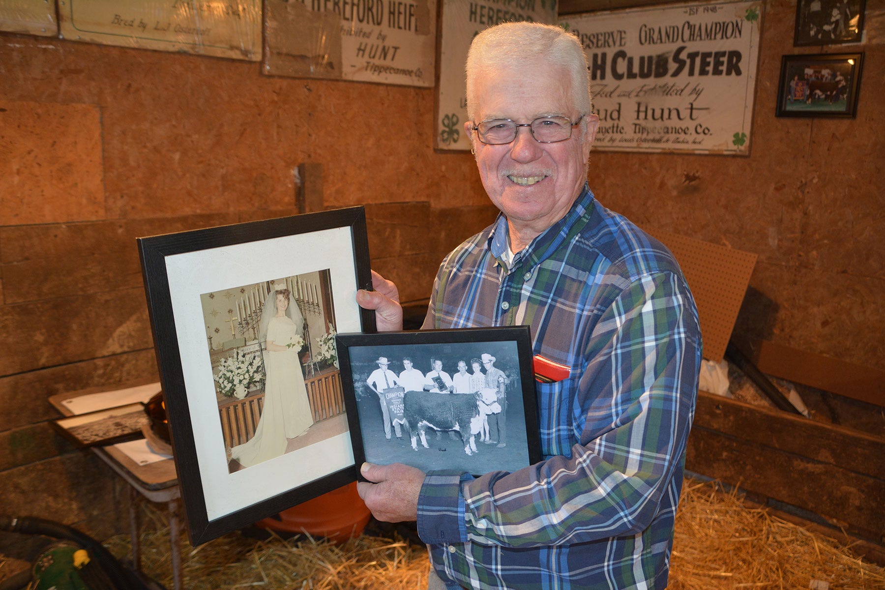 Ted Hunt holding two framed photos -- one of his bride and one of a group of people with a steer